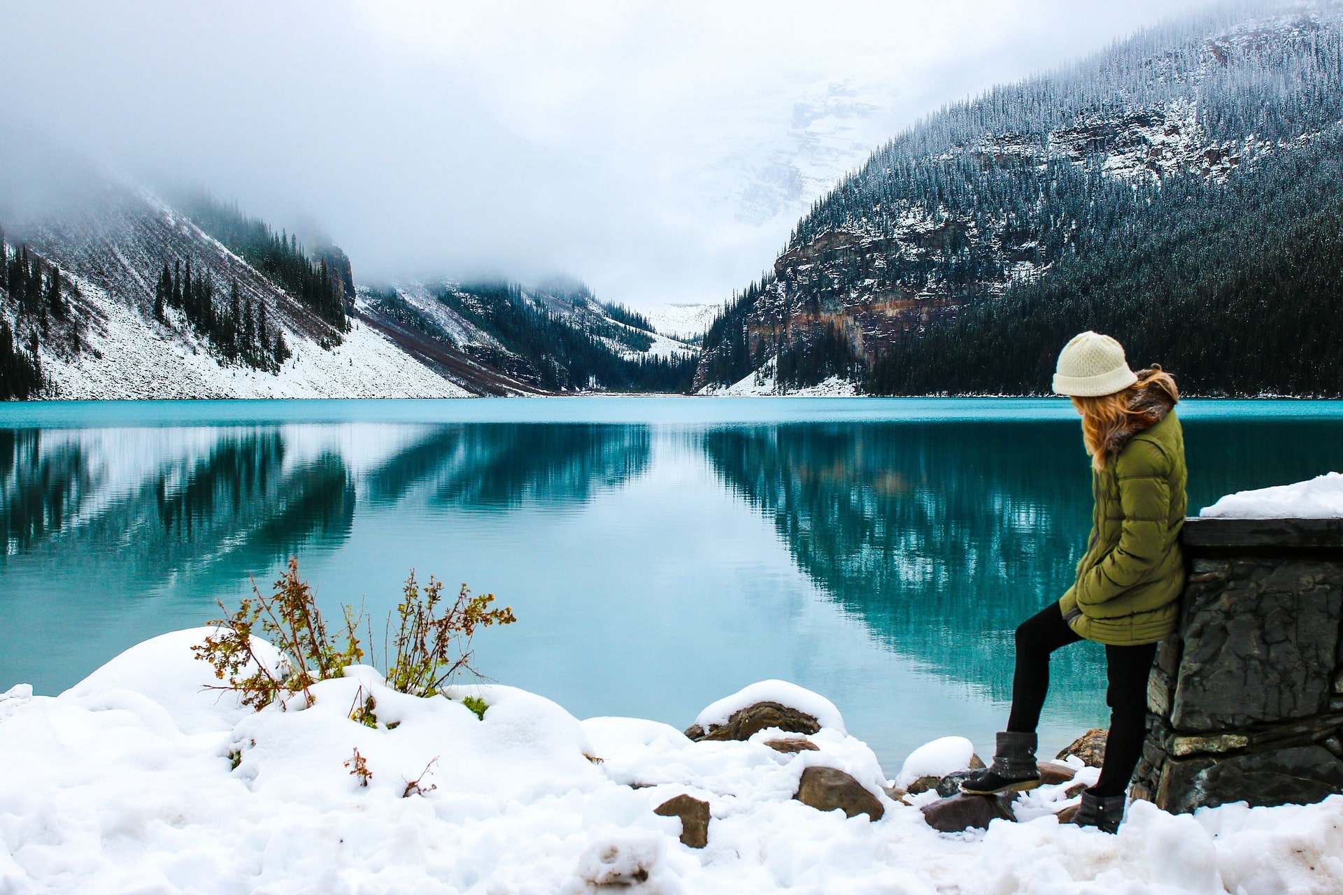 Woman standing in front of lake in winter.